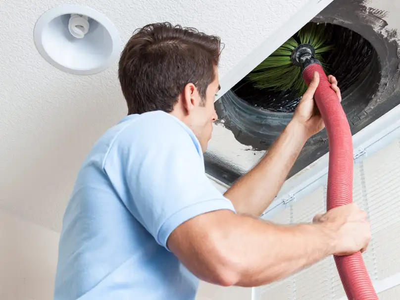 a man doing Air Duct Cleaning in Dallas in a ceiling